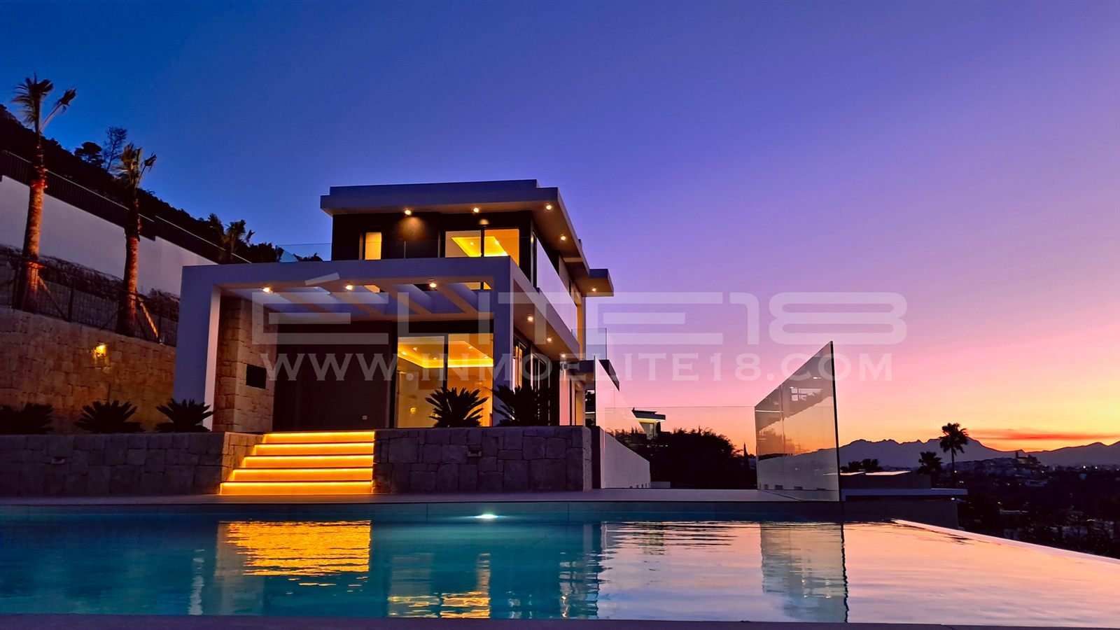 Villa Elysia iluminada al anochecer sobre la piscina infinita